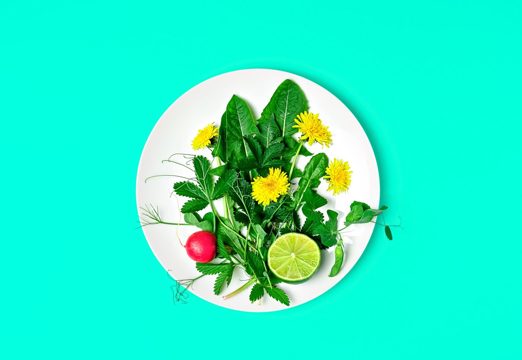 Ingredients for a fresh green salad with dandelions and edible flowers on a plate