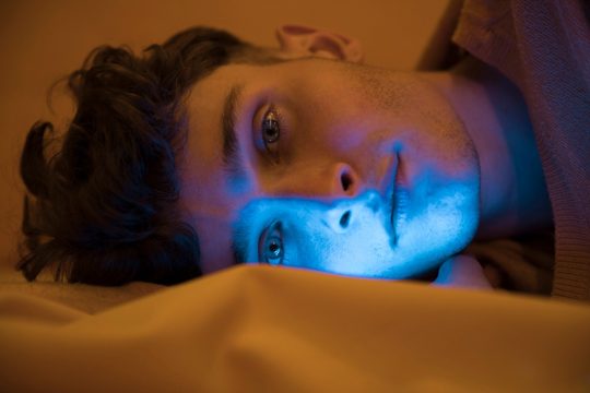 Portrait of fashionable boy relaxing in bed