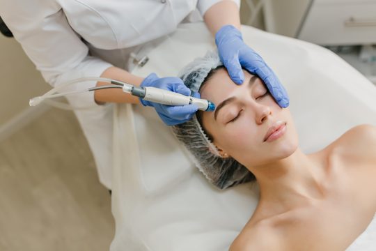 View from above rejuvenation of beautiful woman enjoying cosmetology procedures in beauty salon. dermatology, hands in blue glows, healthcare, therapy, botox