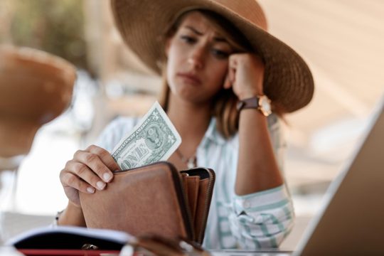 Closeup of worried woman having one dollar bill in her wallet