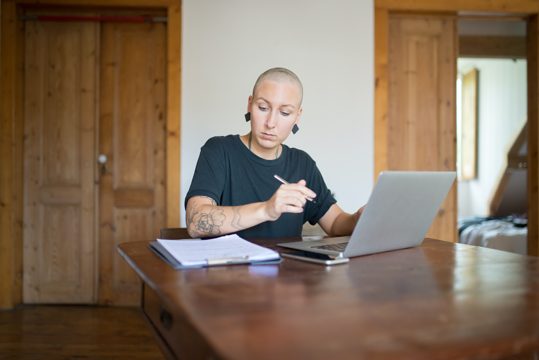 A Bald Woman Working From Home Using Her Laptop