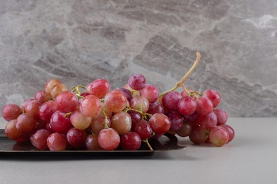 Red grapes on a small tray on marble