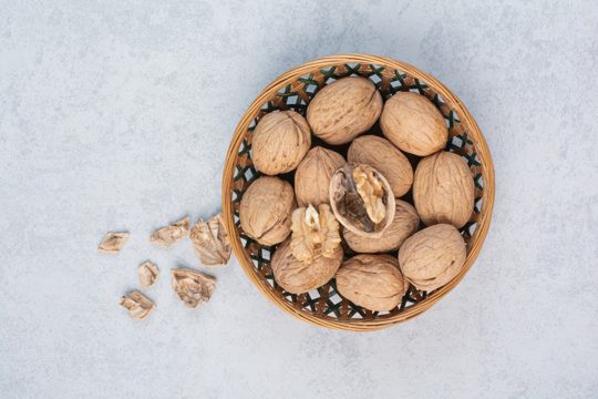 Bunch of walnuts and kernels in ceramic bowl