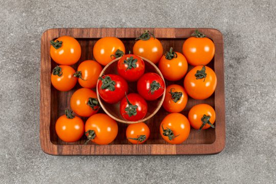 Top view of pile of cherry tomatoes on wooden plate.