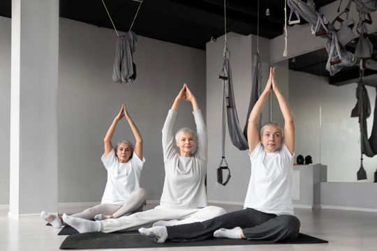 Senior women doing yoga exercises at the gym on yoga mats