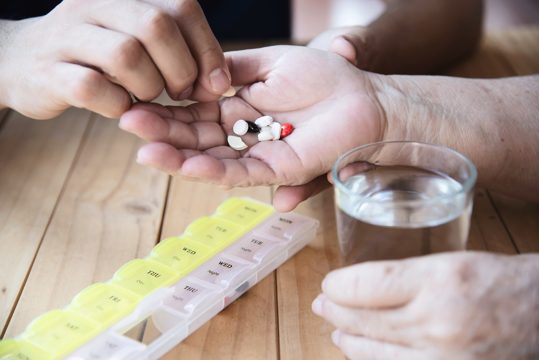 Doctor is assist patient to eat medicine tablet in pillbox correctly