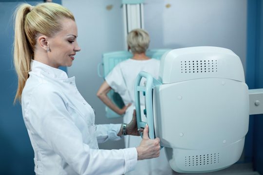 Mid adult smiling nurse taking xray of a patient at clinic