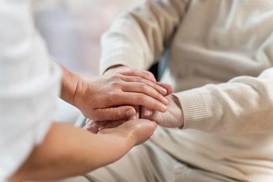 Doctor holding hands with senior patient
